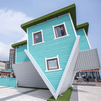 A blue house upside down on an open space.