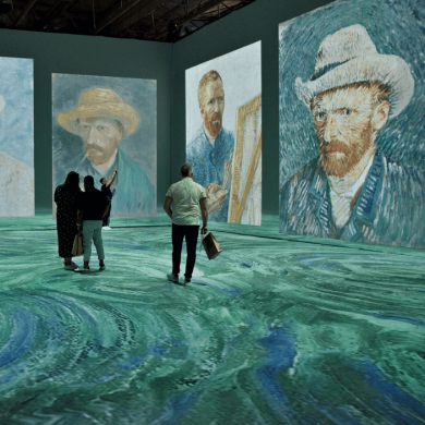 An exhibition inside a large room with projections of Vincent Van Gogh across the walls and floors.