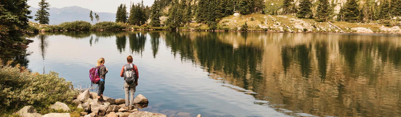 Hikers standing next to an alpine lake in the backcountry