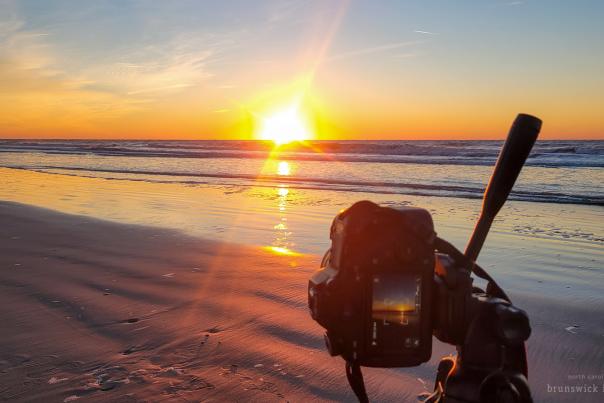 a professional camera on a tripod taking a photo of a sunrise over the ocean
