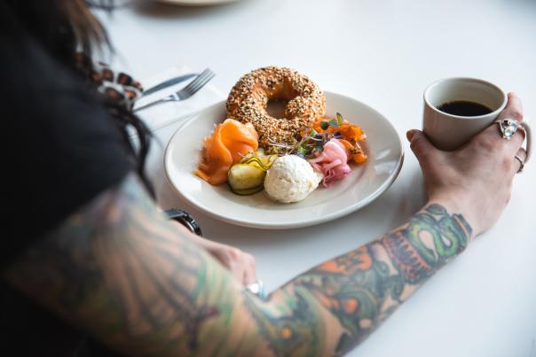 woman with cup of coffee and plate with bagel from bernbaum's