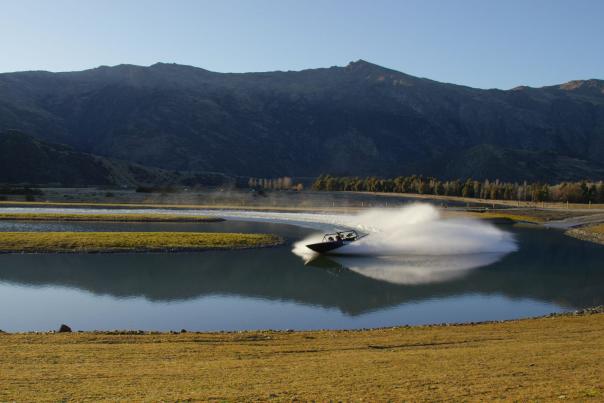 Jet boat on a lake in front of mountains