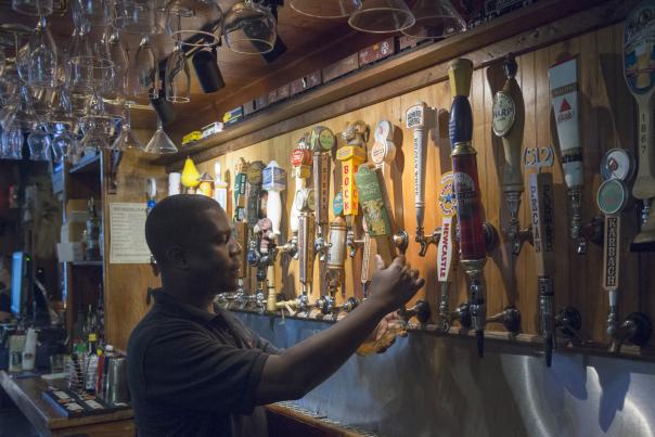 Bartender pouring beer at wall of taps