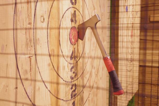 An axe is lodged near the bullseye of a wooden circle target.