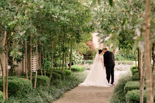 Bride and groom walking down tree lined path