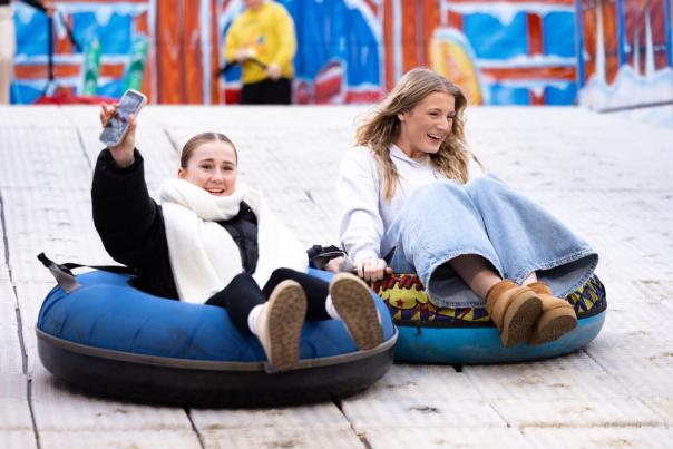 Two girls sliding down the big snow slide at the Christmas Market