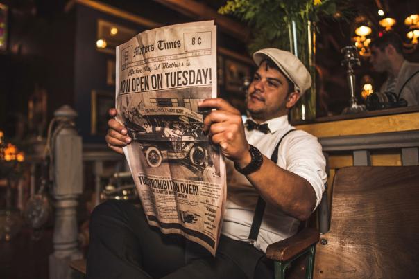 A man in 1930s clothing reading a newspaper at Mathers Social Gathering speakeasy in Downtown Orlando.