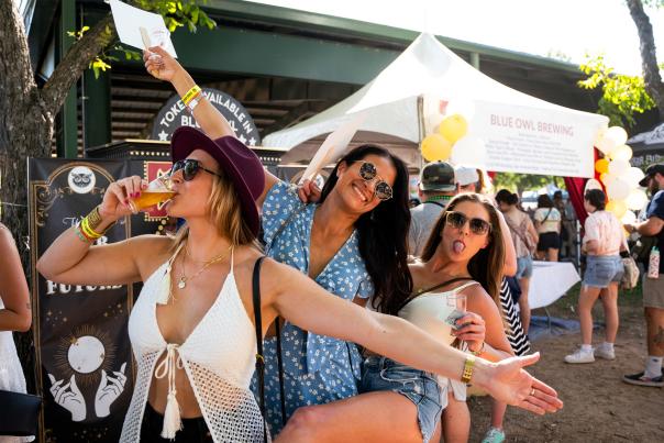 Photo of three women smiling towards the camera and drinking beer at the Texas Craft Brewers Festival.