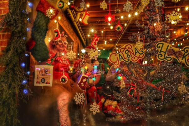 People dressed up in holiday costumes surrounded by holiday decorations.