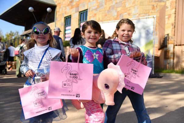 Three children dressed in Halloween costumes, attending the Haunt the Zoo event at OKC's Zoo.