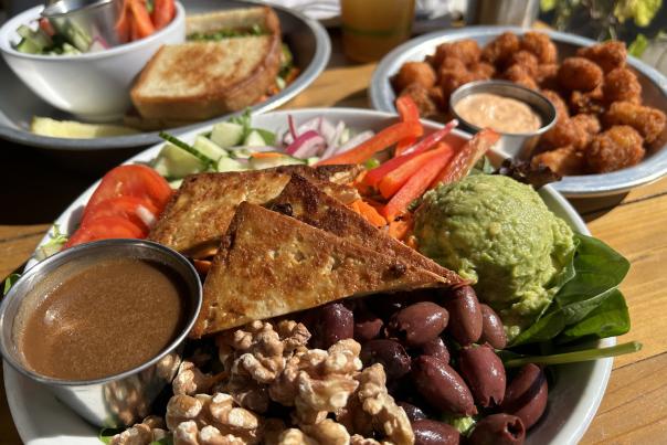 Places of vegeterian plates sit on wooden table.