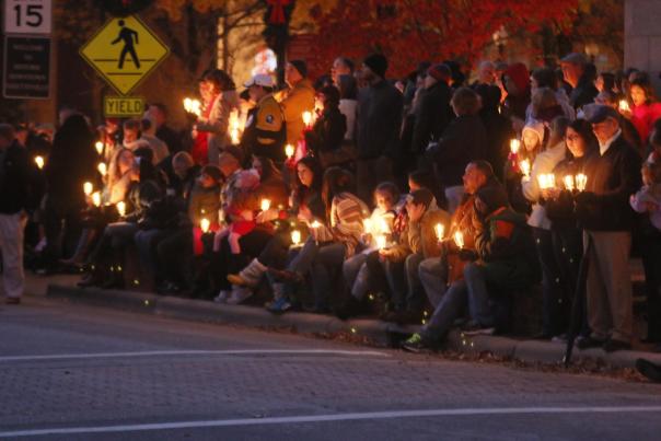 A crowd gathers downtown in Fayetteville, North Carolina, holding candles during the annual Dickens Holiday celebration.