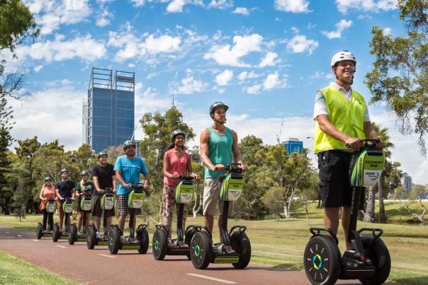 Group segway tour cruising along the path, with the city skyline in the background.
