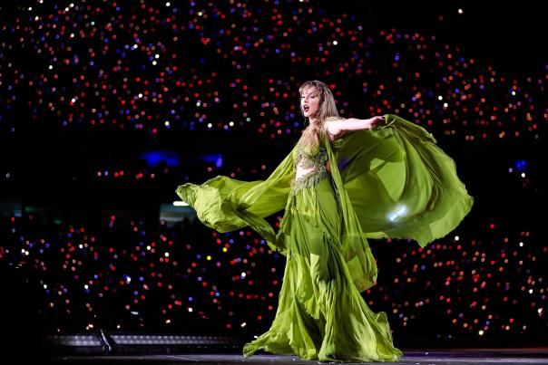 Taylor Swift during the Eras Tour on stage in a green dress