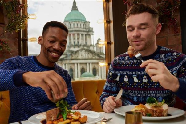 Two men enjoying a festive meal at Cafe Parisien in their Christmas jumpers