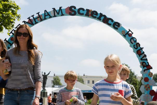 A family walking towards the camera with the Cheltenham Science Festival entrance arch in the background