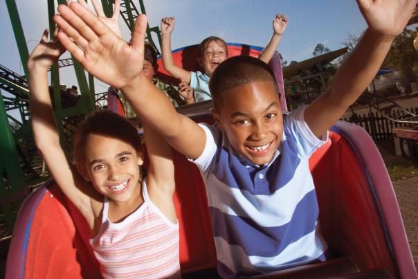 A boy and girl riding a roller coaster at a theme park