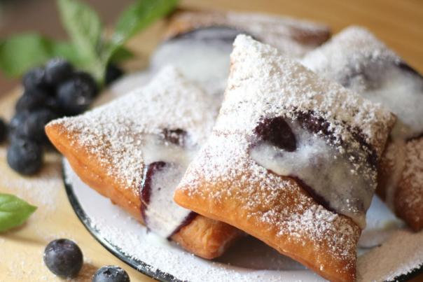 A plate of blueberry beignets sprinkled with powdered sugar
