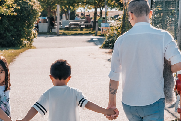 two parents walking hand in hand with their children