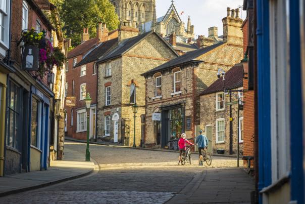cyclists stood by bikes with historic houses and cathedral in background