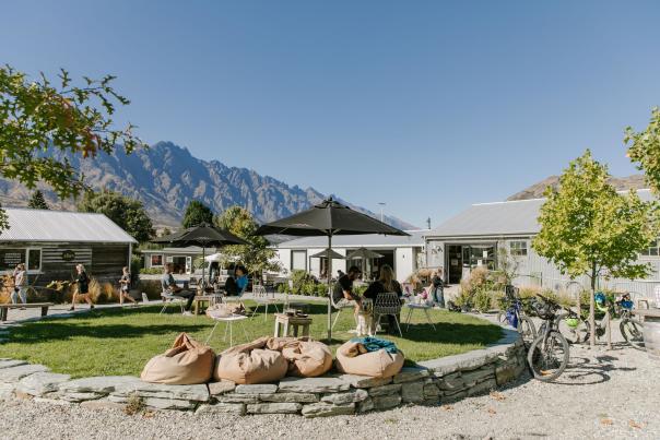 A collection of boutique shops and people sitting around a green park