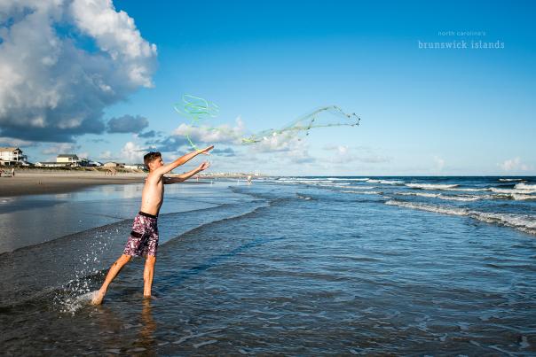 a boy throwing a cast net into the ocean