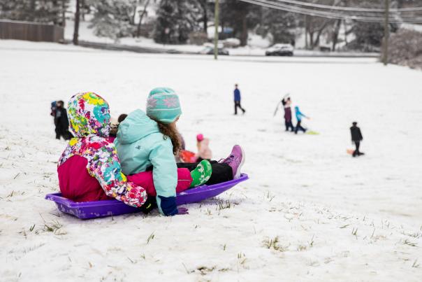 Two kids sledding down a hill.