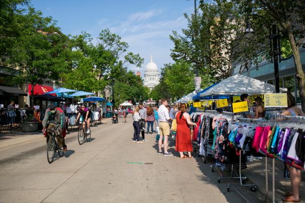 A wide view of State Street looking toward the Capitol with dozens of people shopping from racks on the sidewalk during the Maxwell Street Days