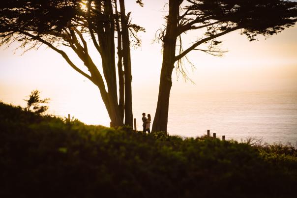 Couple taking engagement photos overlooking the Pacific Ocean