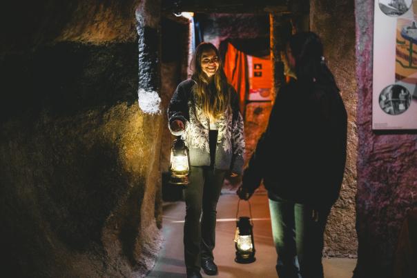 Two people, holding lanterns, walking through Nanaimo Museum's coal exhibit.