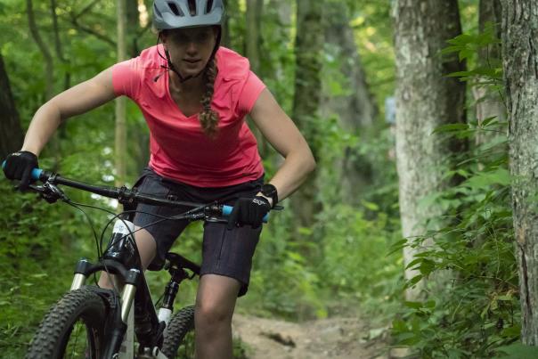 Mountain biker with pink shirt riding through a trail near Grand Rapids