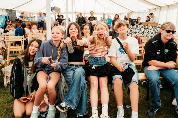 teenagers sitting on a bench in a festival tent posing