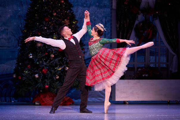 A couple dances in front of a Christmas tree.