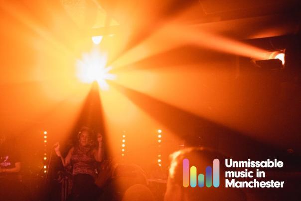 person performing on stage to a crowd of people with Unmissable Music in Manchester logo