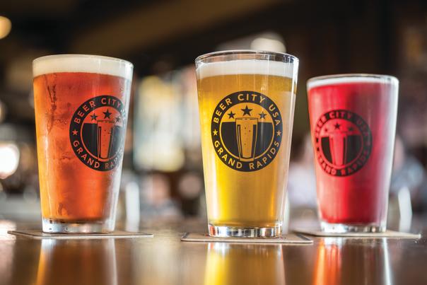 Three pint glasses that read 'Beer City USA Grand Rapids' filled with different beers.