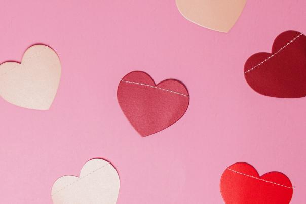Photograph of red and cream paper hearts on a pink background