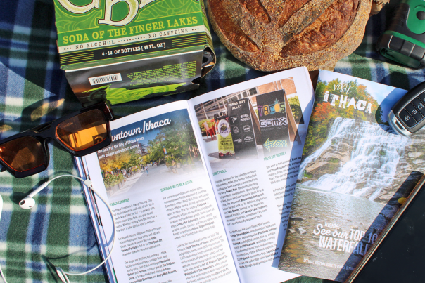 Travel guide open on picnic blanket with bread