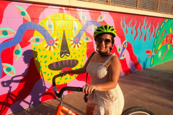 Girl with bike helmet on bike in front of mural