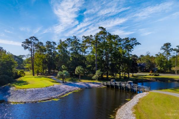 a golf course hole divided by a wooden bridge