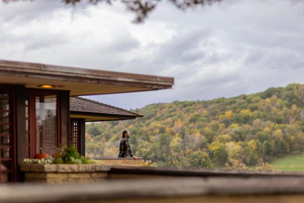 A woman looks out onto the rolling hills of Spring Green from the balcony at Taliesin