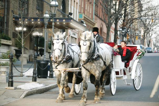 Horse-drawn carriage rides in Bethlehem PA with white horses and couple in white carriage on Main Street