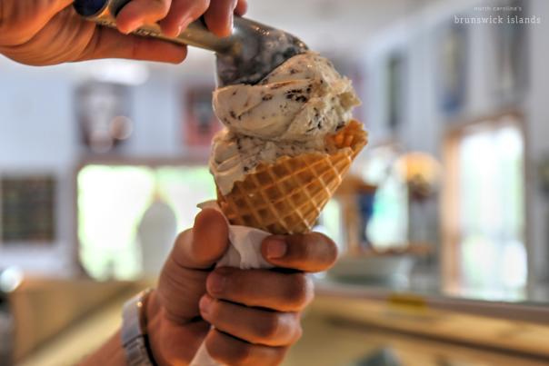 A pair of hands scooping ice cream onto a cone at the Calabash Creamery