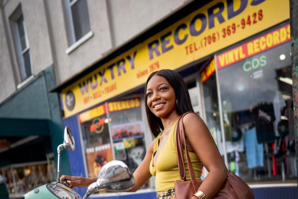 A woman stands next to a green scooter outside of Wuxtry Records in downtown Athens.