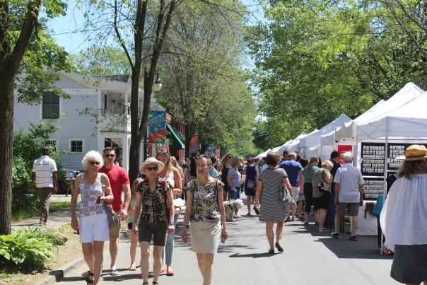 Sidewalk shot of many attendees walking alongside vendor tents on Beekman St