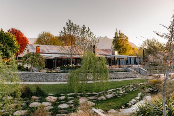 Exterior of The Woolshed Restaurant, Ayrburn with autumn coloured trees and distant mountains in the background