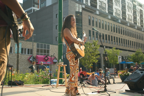 Women with guitar playing and singing on stage in the summer in downtown Lansing