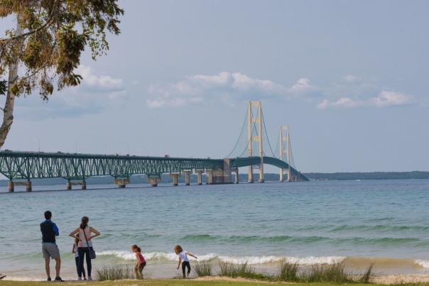 A family at the beach in the Upper Peninsula with the Mackinac Bridge in the background