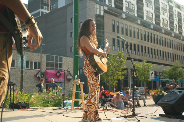 Women with guitar playing and singing on stage in the summer in downtown Lansing