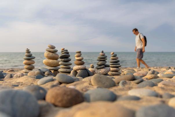 rocks stacked on top of each other and a man walking along beach behind them