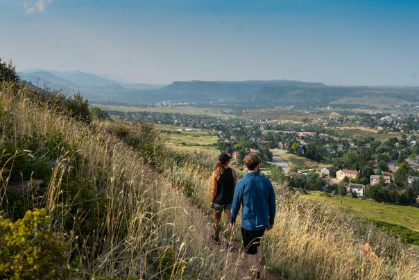 Two people walking on Nightbird Trail, Mount Galbraith overlooking north Golden, CO in the spring.